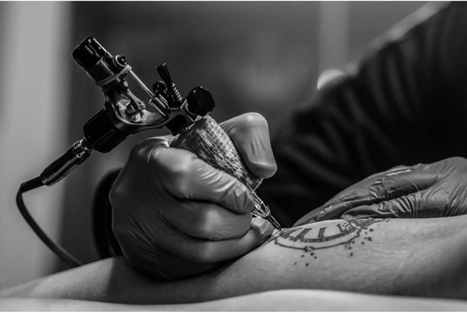 A tattoo artist making tattoo on a client's body with his tattoo gun